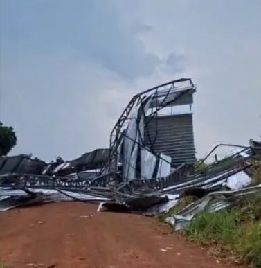 Estrutura metálica de curral recém-construído ficou parcialmente destruída após a força do vendaval, com destroços espalhados pela estrada - Imagem: Captura de Tela.